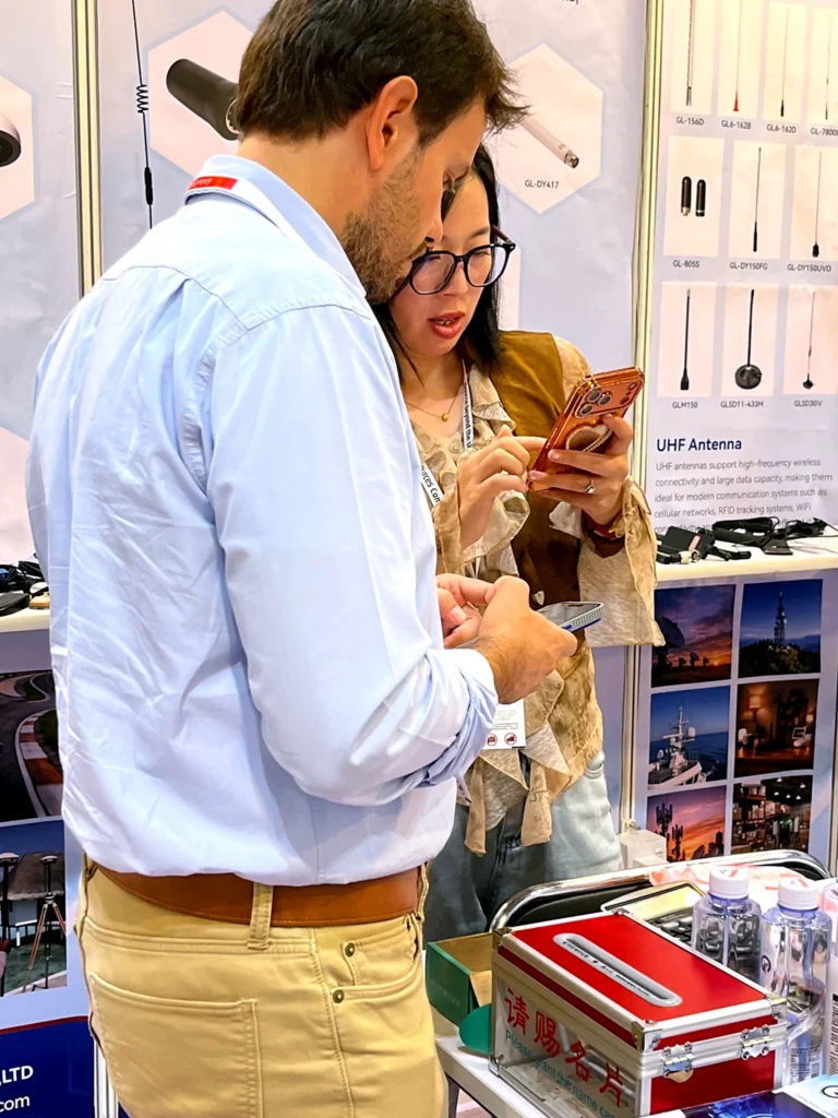 Global RF Tech representative showing antenna product details to visitors at the Hong Kong exhibition.